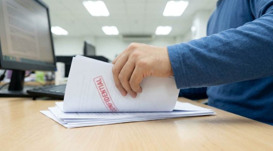 Employee sorting labeled confidential documents before shredding